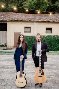 a man and woman standing next to each other holding guitars